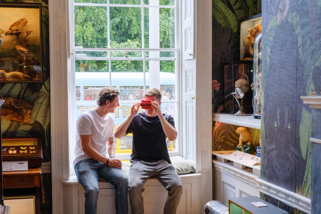 Two guests sitting in the window of the Animals of Dublin room, one looking at a vintage viewmaster