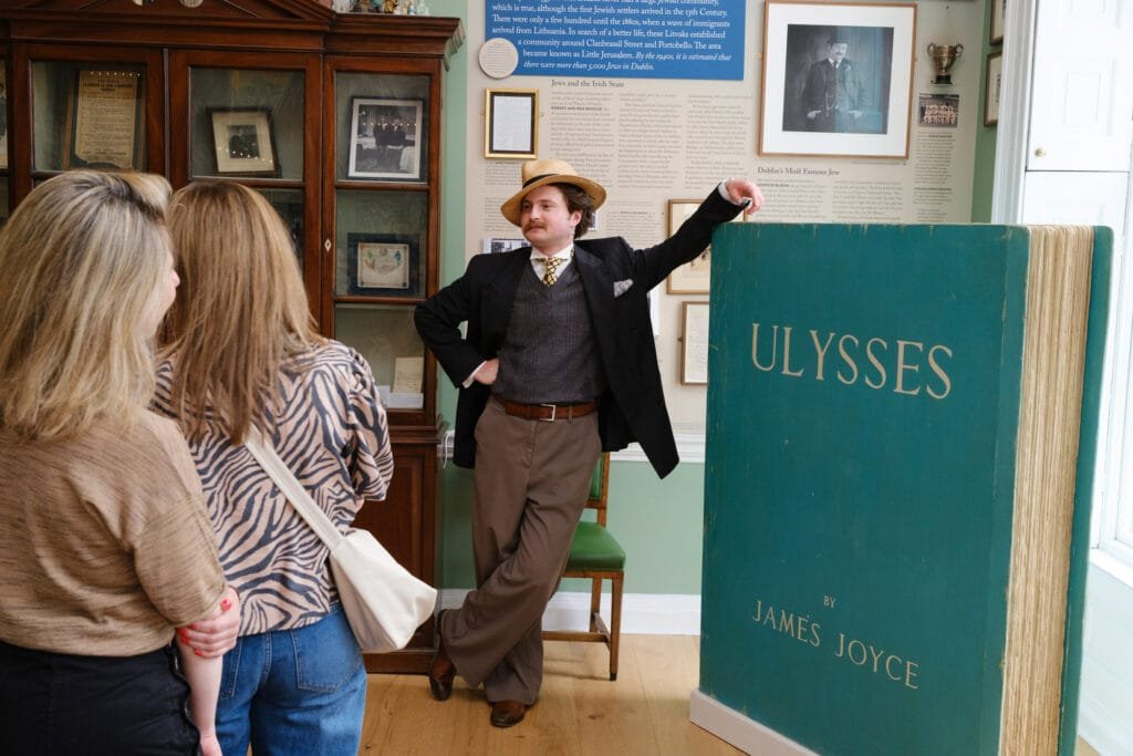 A Little Museum tour guide leaning on an oversized copy of Ulysses by James Joyce