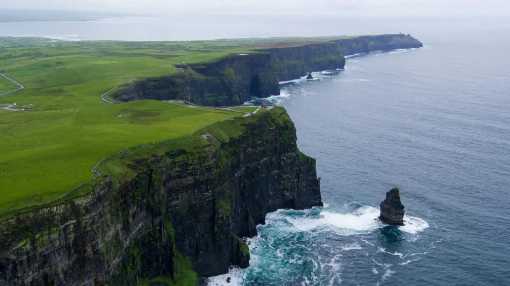 Impresionante vista aérea de los acantilados de Moher, condado de Clare, Irlanda, con exuberantes paisajes verdes y olas del océano.