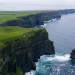 Stunning aerial view of the Cliffs of Moher, County Clare, Ireland with lush green landscapes and ocean waves.