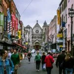 A bustling street scene in Dublin, showcasing diverse people and historic architecture.