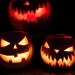 Three glowing jack-o'-lanterns at night, creating a spooky Halloween atmosphere.