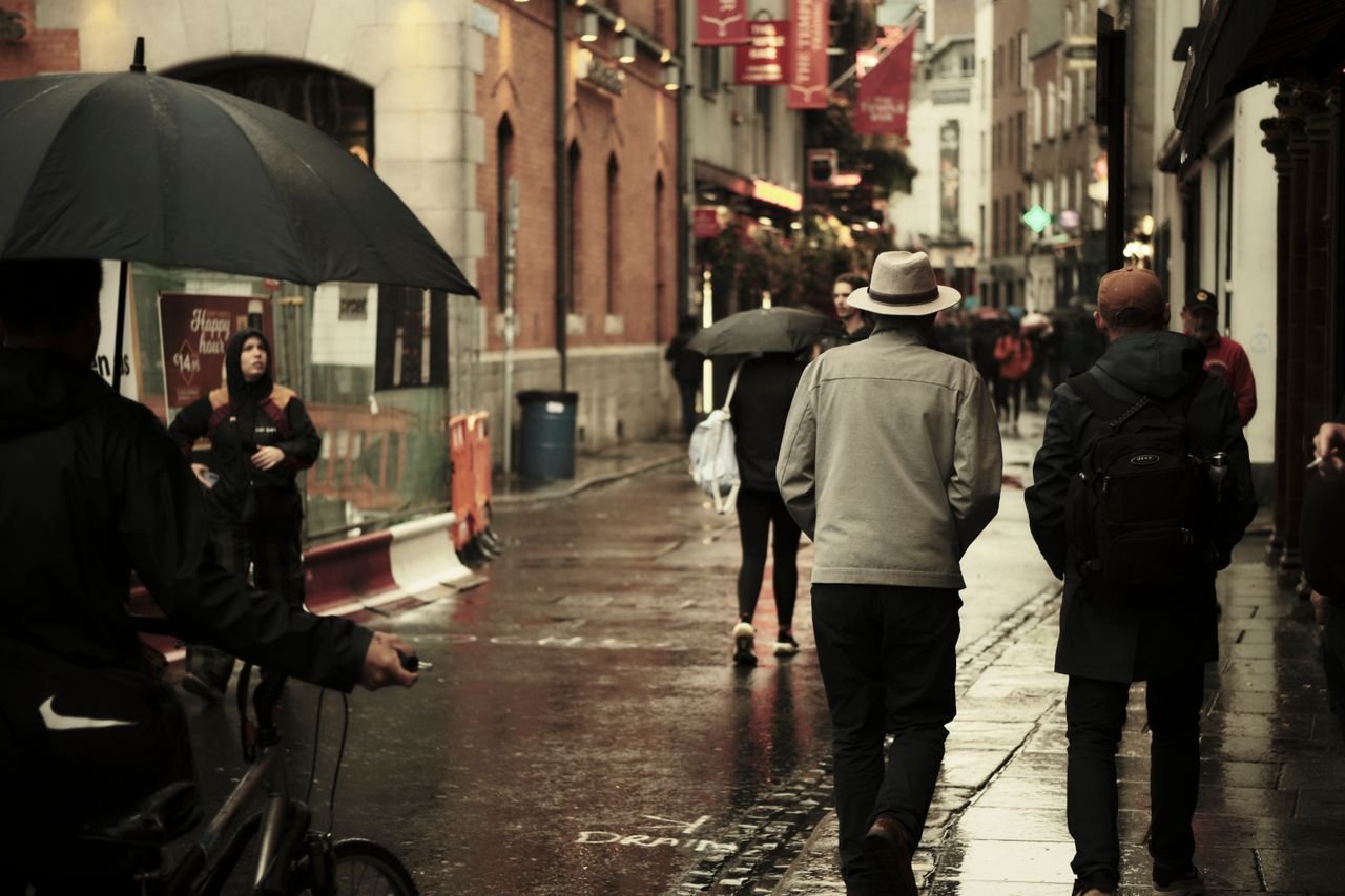 Rainy urban street scene in Dublin, Ireland with pedestrians and umbrellas.